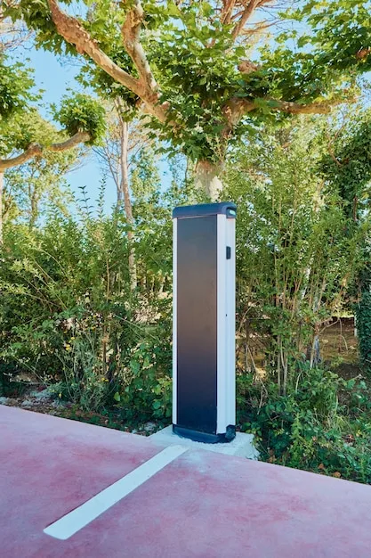 A sleek electric vehicle being charged at a public charging station, surrounded by modern urban architecture.