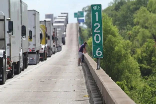 A long line of semi-trucks backed up at a US-Mexico border crossing point, with customs officers visible, indicating potential delays due to new tariff compliance or increased checks.