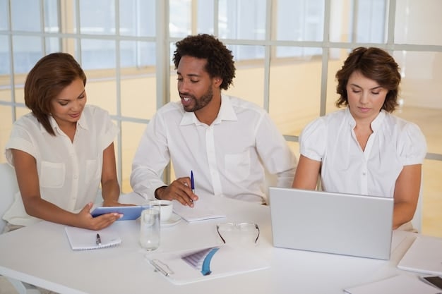 A diverse group of US and Mexican business professionals in a collaborative meeting, showcasing a successful cross-cultural partnership with documents and laptops on a conference table.