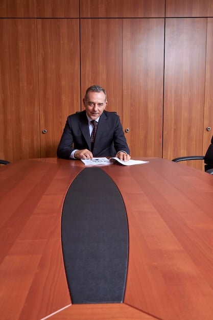 A legal expert in a suit, sitting at a table with a Mexican and US flag, gesturing towards legal documents and a laptop, symbolizing bilateral legal consultations. Bright, professional office setting.