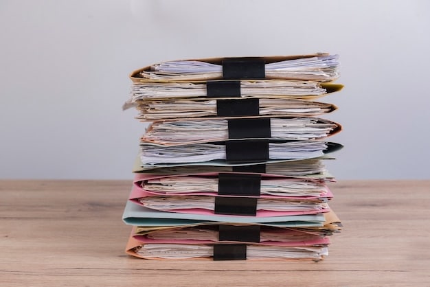 A stack of neatly organized documents, including tax forms, utility bills, and bank statements, on a wooden desk with a 