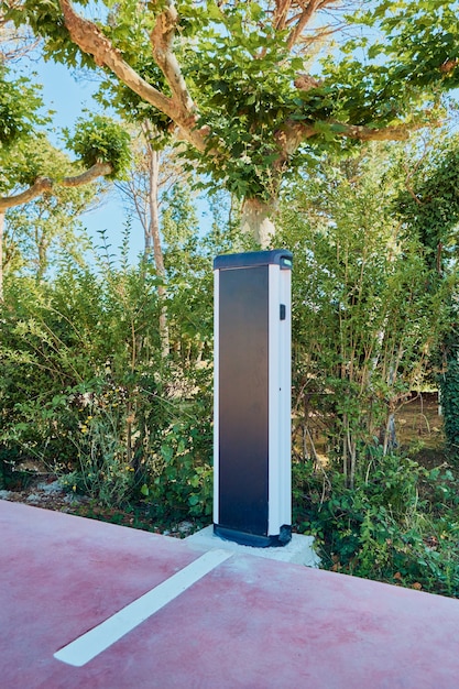 A sleek electric vehicle being charged at a public charging station, surrounded by modern urban architecture.
